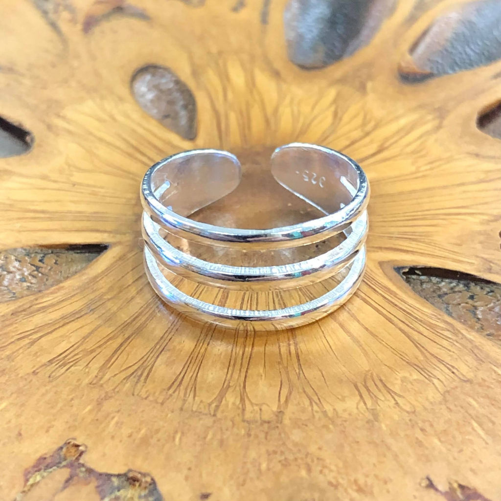 A triple band sterling silver ring on a wooden background