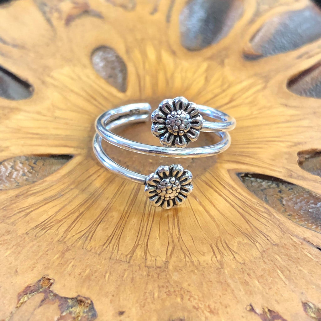 A toe ring featuring a sunflower design on a wooden background