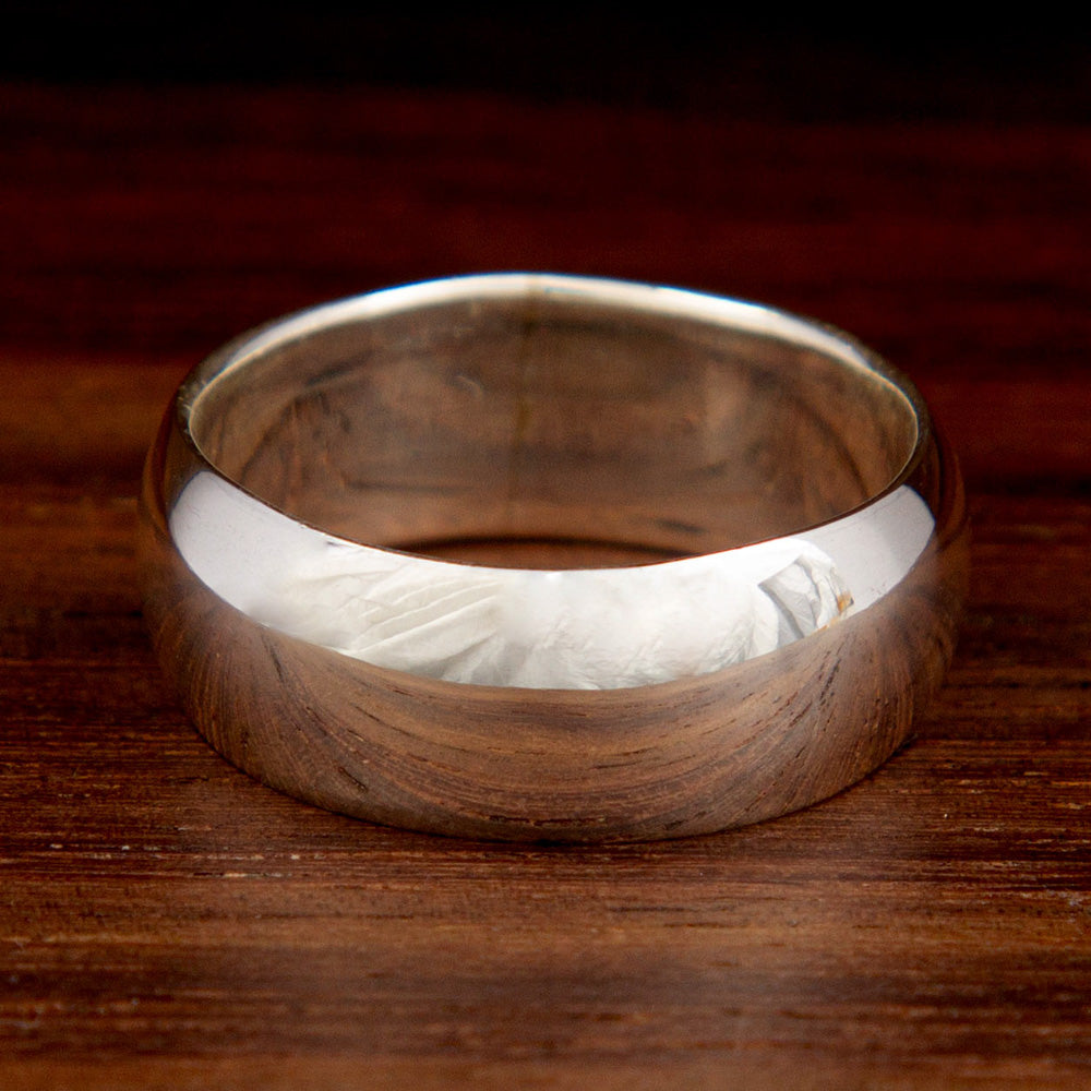 A silver thick band ring on a wooden background