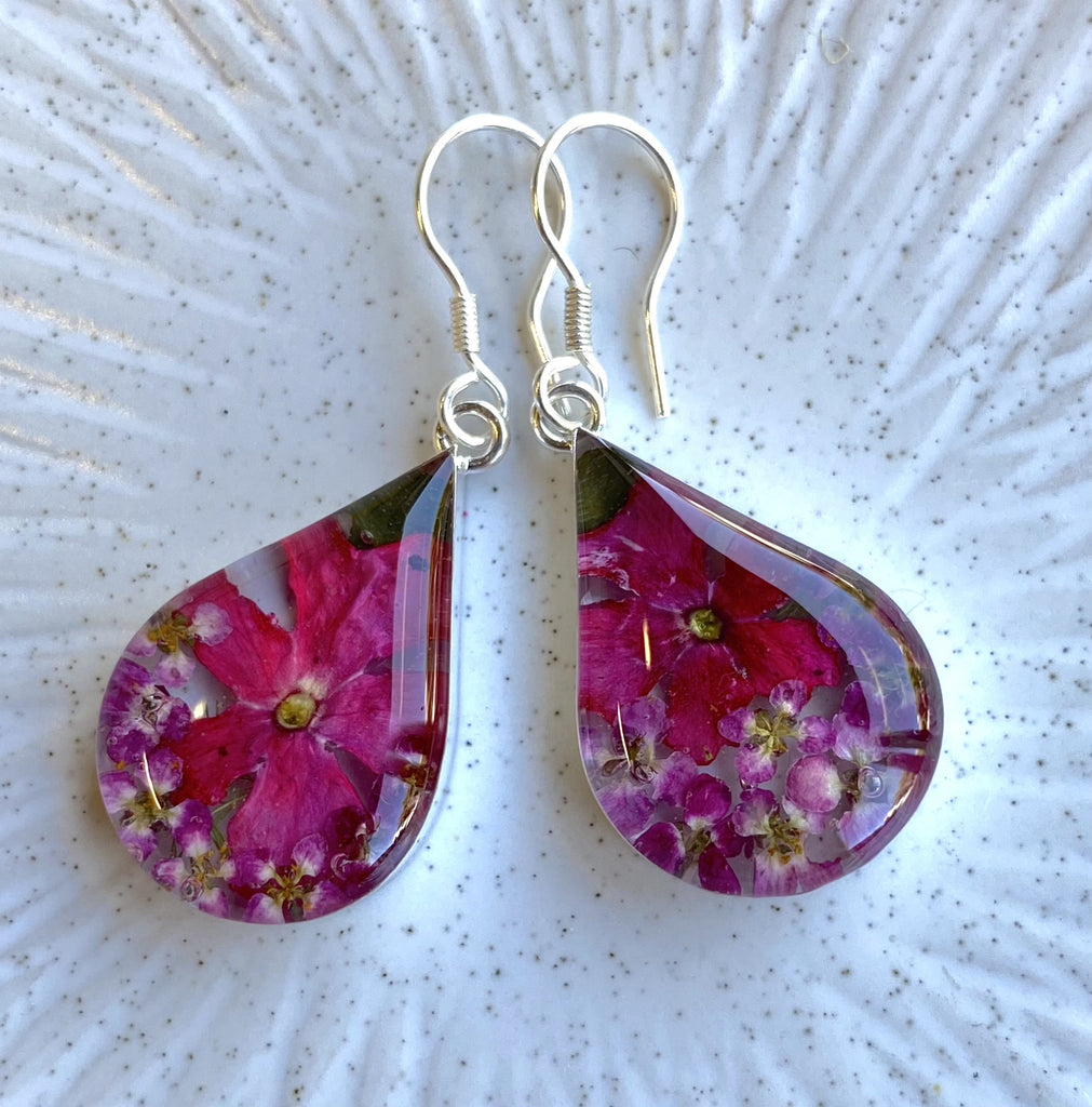san marco medium length teardrop shaped silver and resin earrings with dried purplish pink flowers encased in the resin