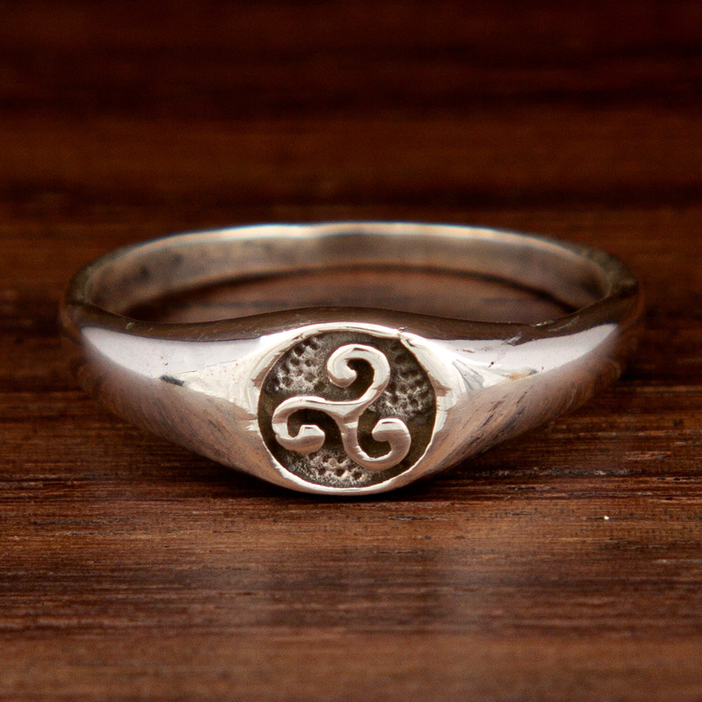 A silver ring with a triskelion symbol 