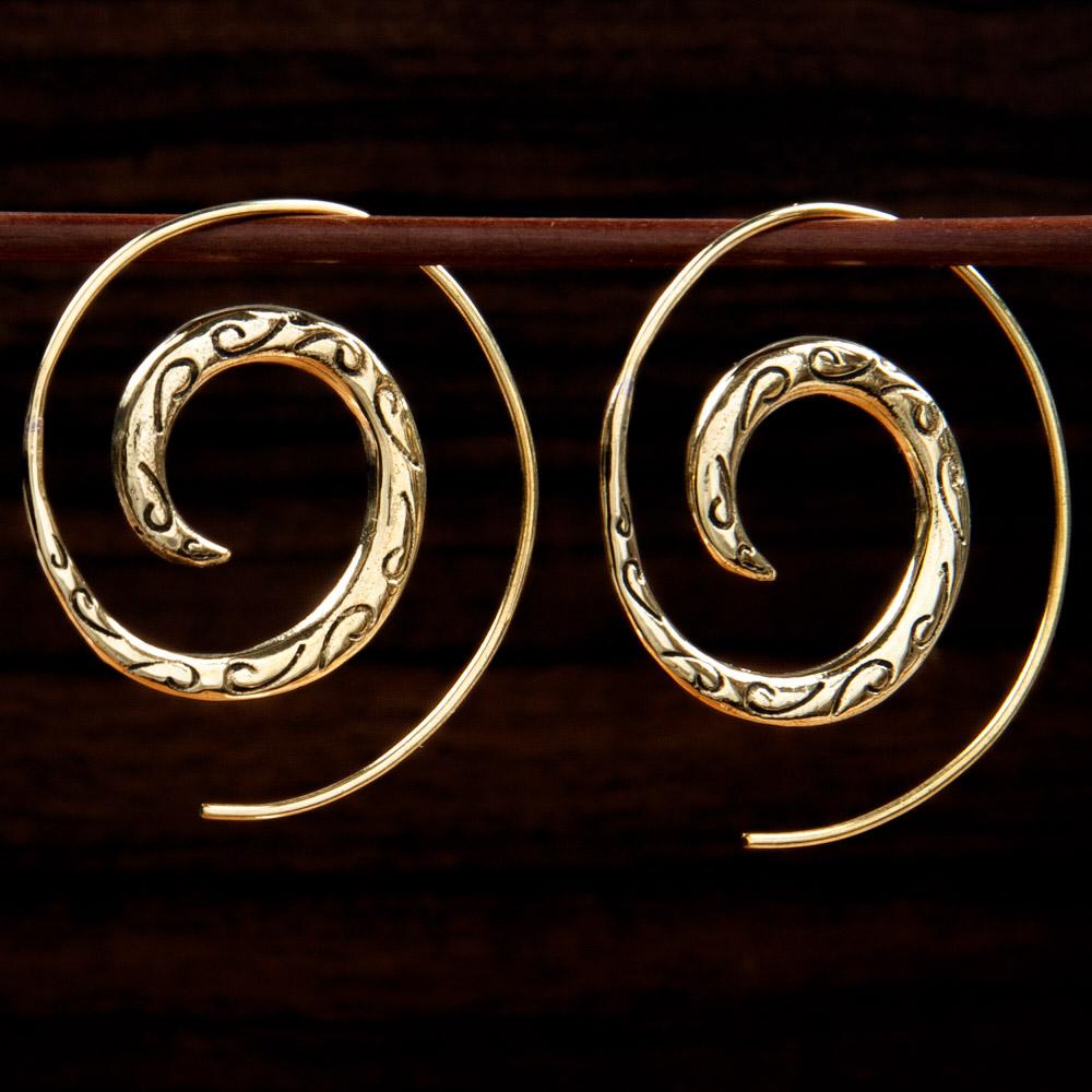 Two handmade brass earrings featuring a spiral design on a dark background