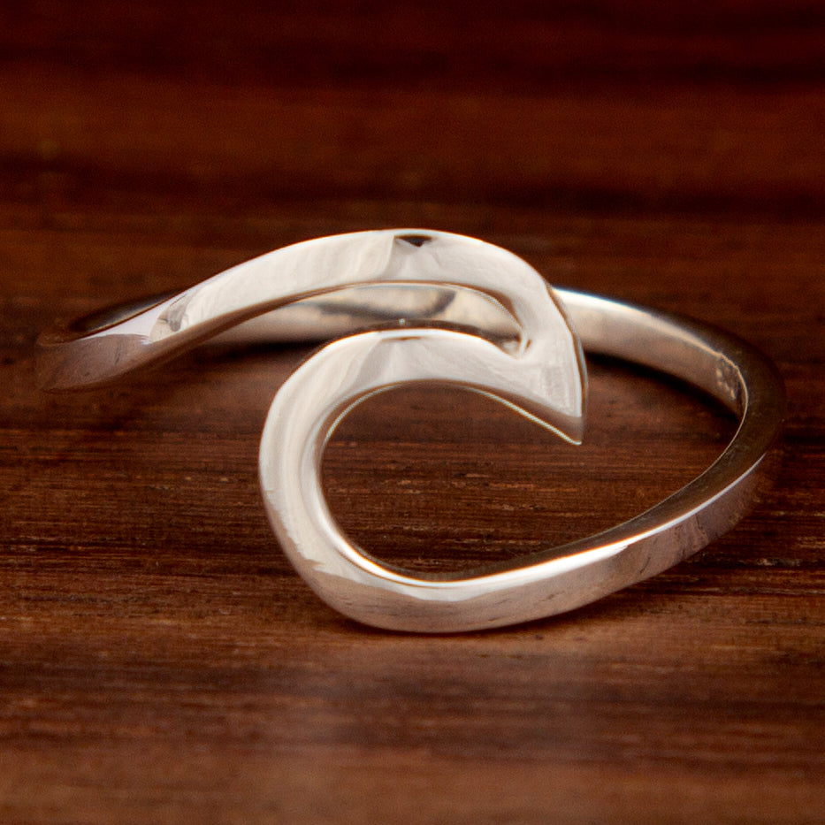 A silver ring featuring a weave design on a wooden background