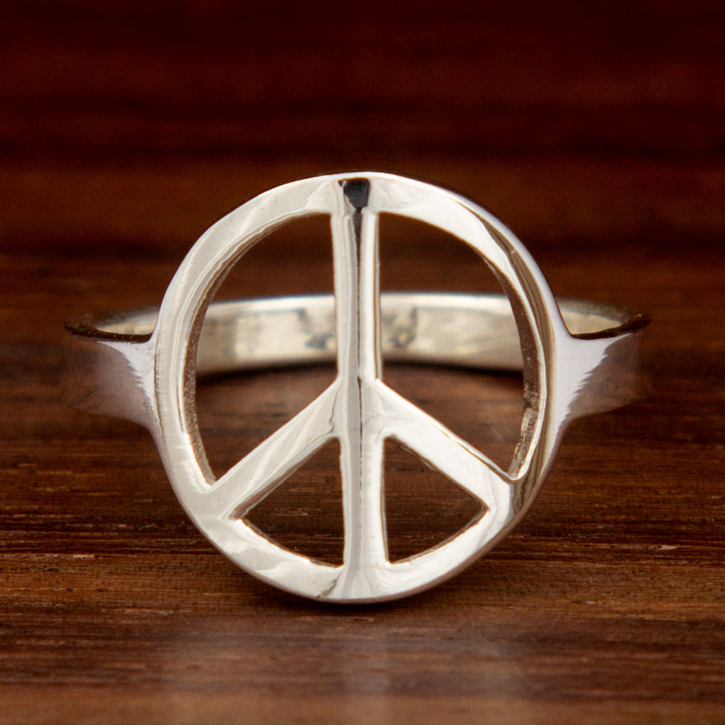 A silver ring featuring a peace symbol on a wooden background