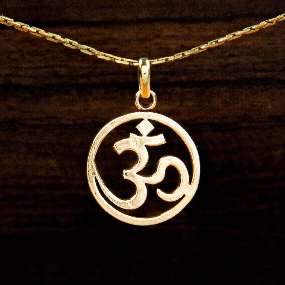 A brass pendant featuring the Om symbol on a wooden background