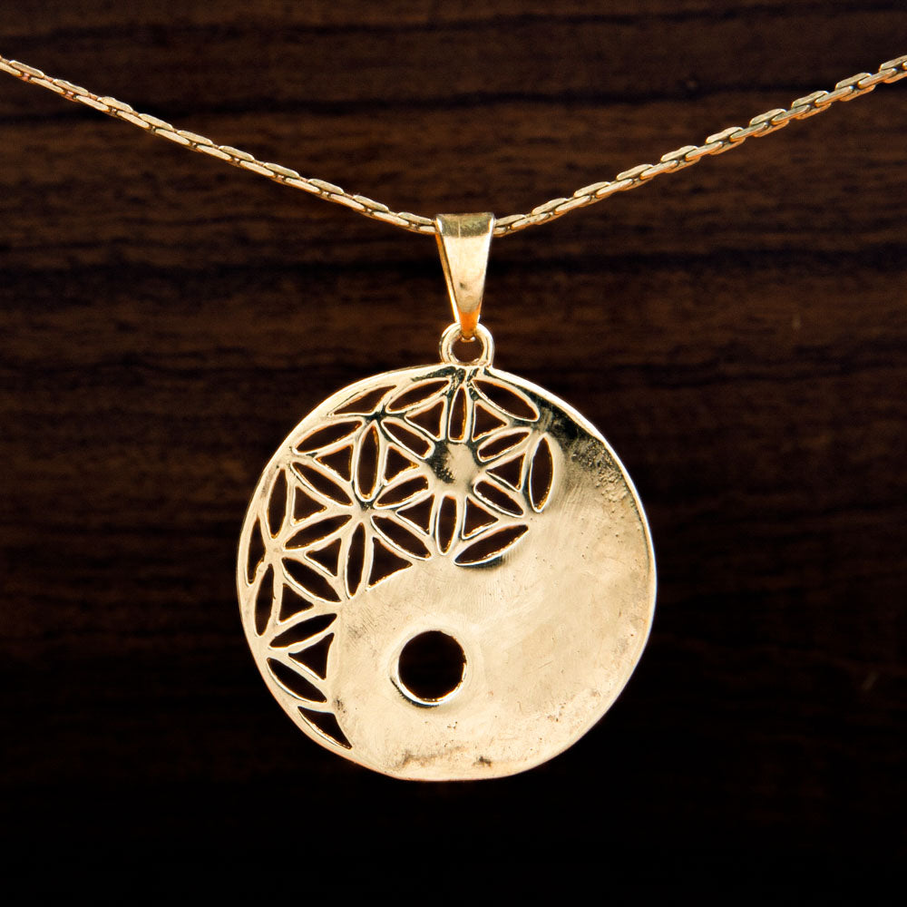 A brass pendant featuring a ying and yang design on a wooden background