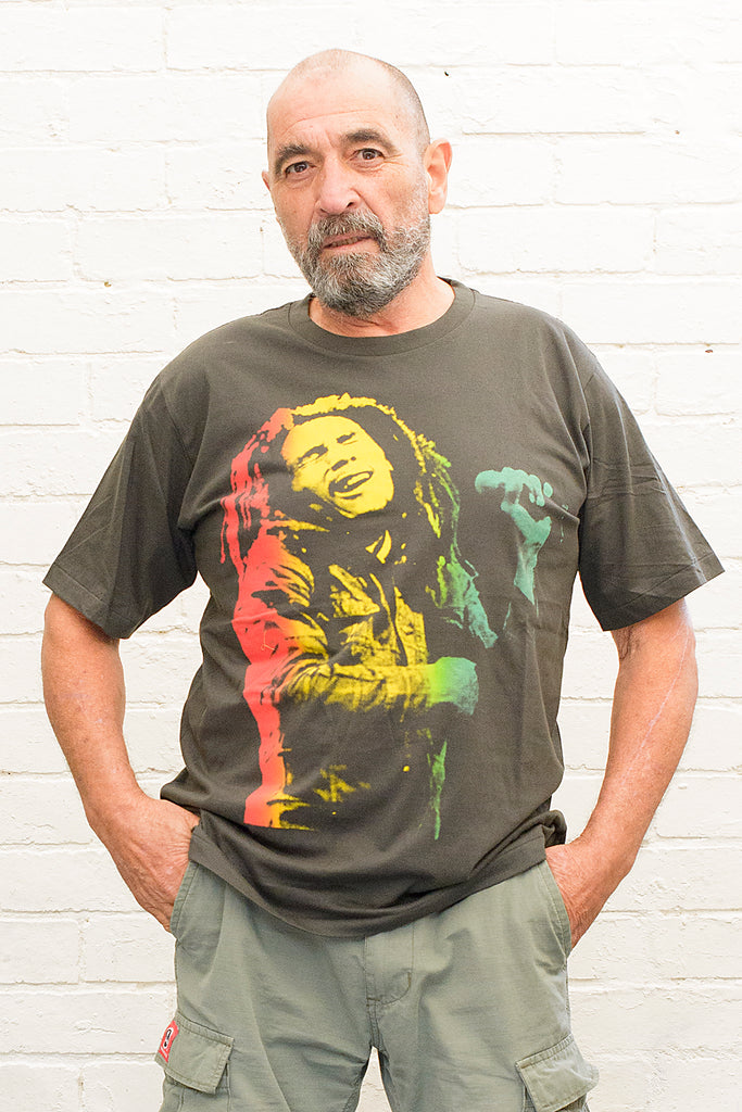 model wearing black cotton t-shirt with a red gold and green toned photographic print of bob marley singing on front