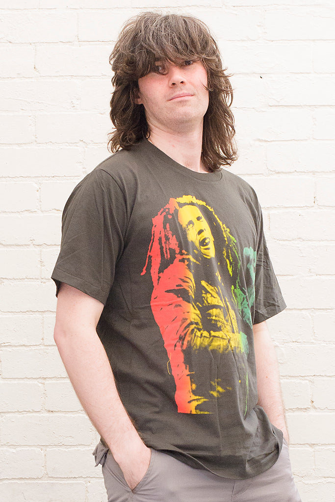 model wearing black cotton t-shirt with a red gold and green toned photographic print of bob marley singing on front