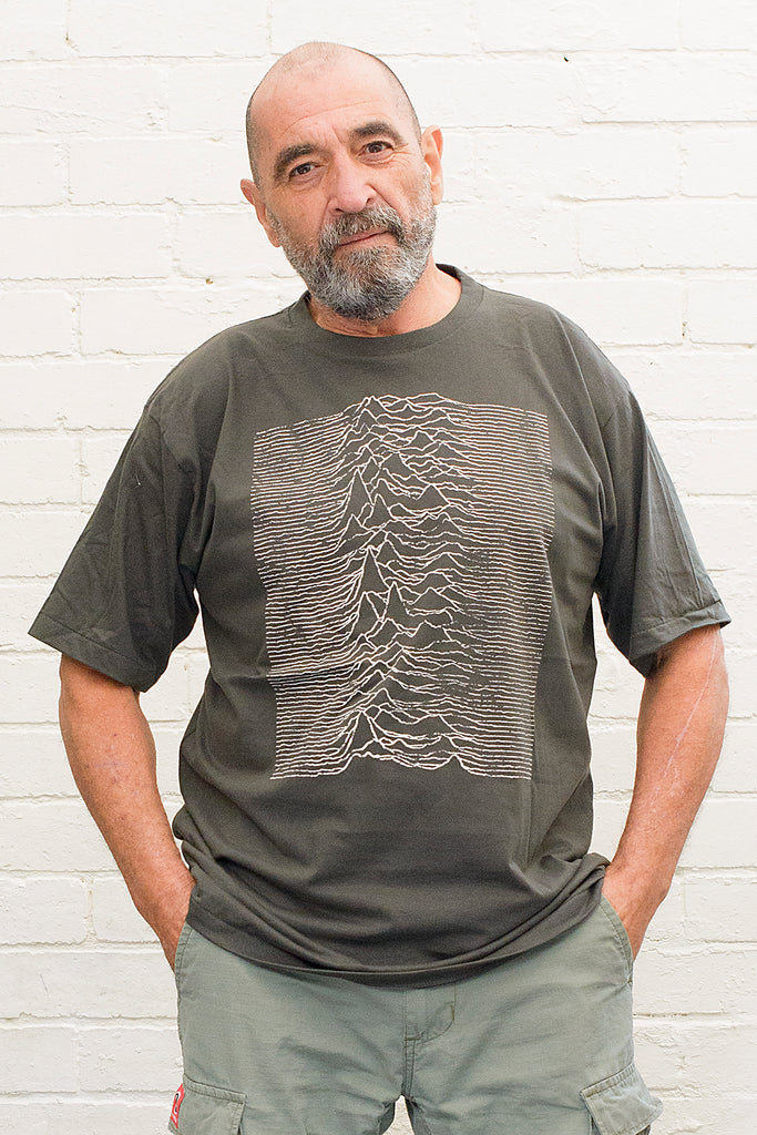 model wearing black cotton t-shirt with graphic from the joy division unknown pleasures album cover print on front