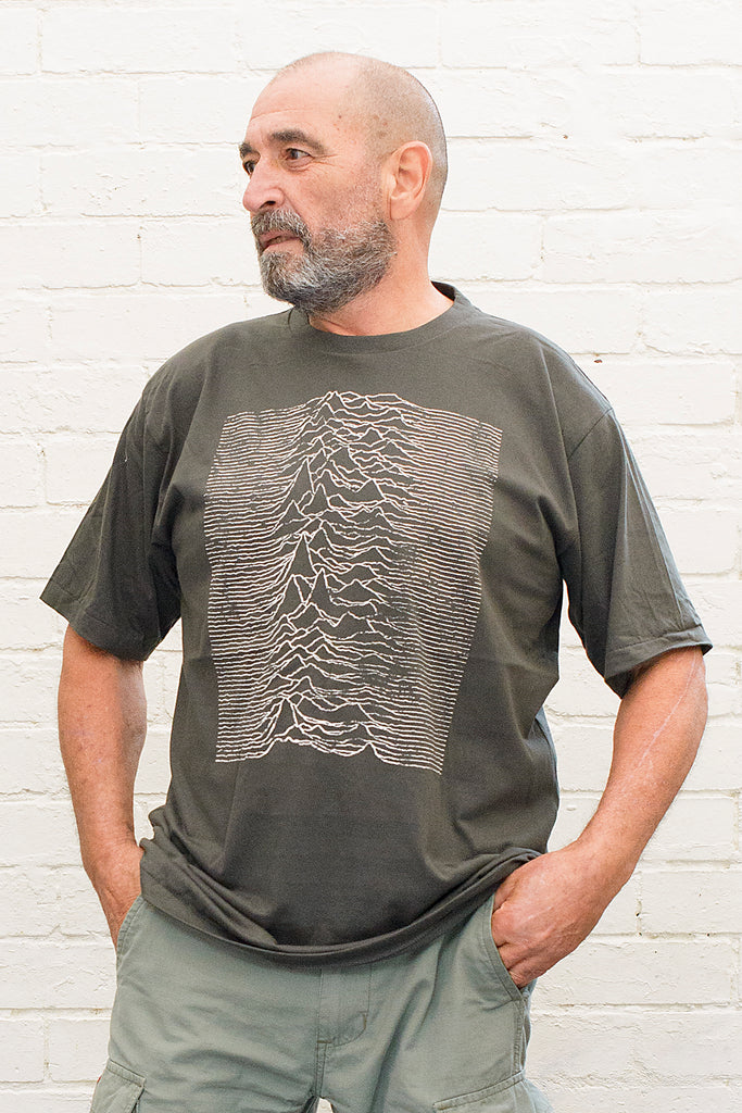 model wearing black cotton t-shirt with graphic from the joy division unknown pleasures album cover print on front