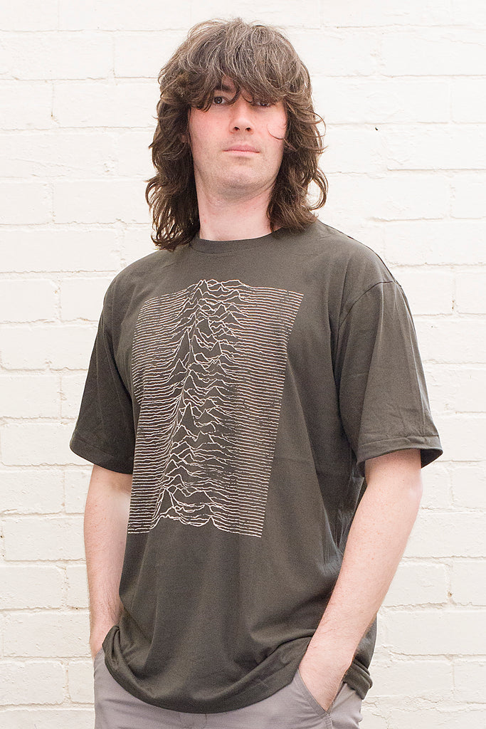 model wearing black cotton t-shirt with graphic from the joy division unknown pleasures album cover print on front