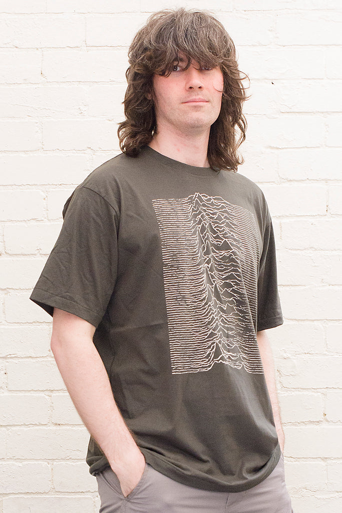 model wearing black cotton t-shirt with graphic from the joy division unknown pleasures album cover print on front