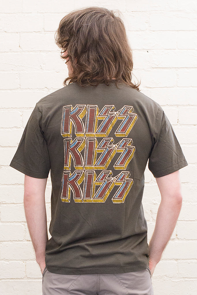 model wearing black cotton t-shirt with kiss logo repeated three times printed on back