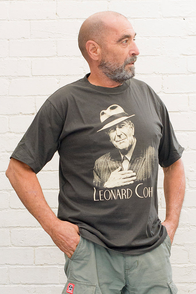 model wearing black cotton t-shirt with image of leonard cohen wearing hat and pinstripe suit with leonard cohen text printed below on front