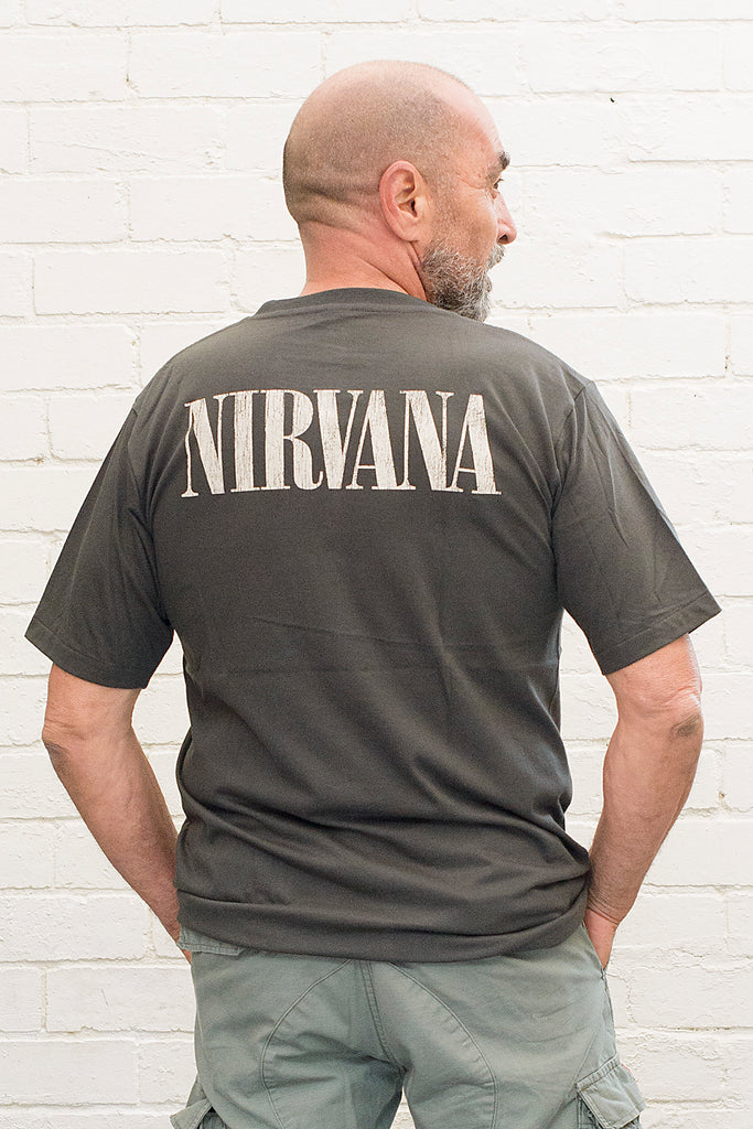 model wearing black cotton t-shirt with Nirvana logo printed on back