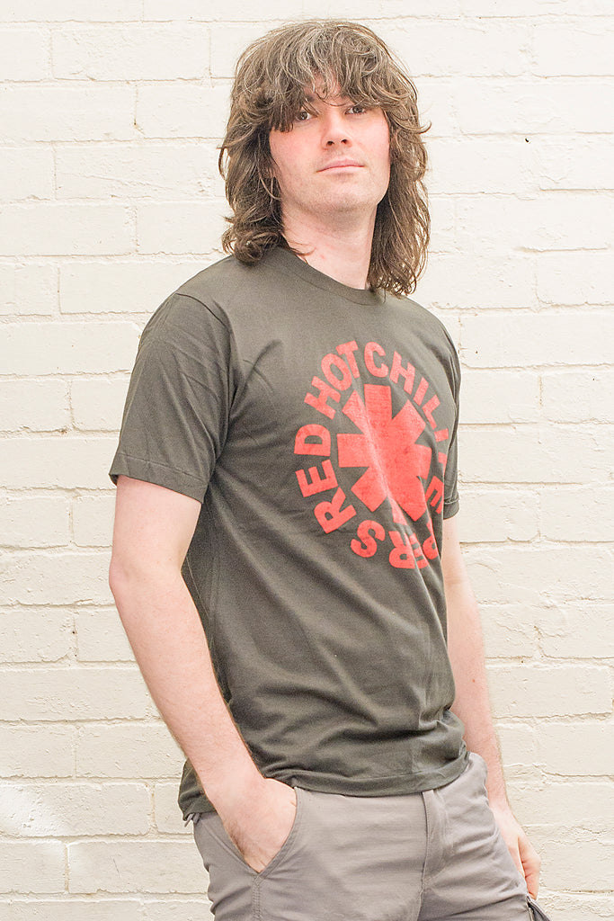 model wearing black cotton t-shirt with red hot chili peppers logo and band name printed on front