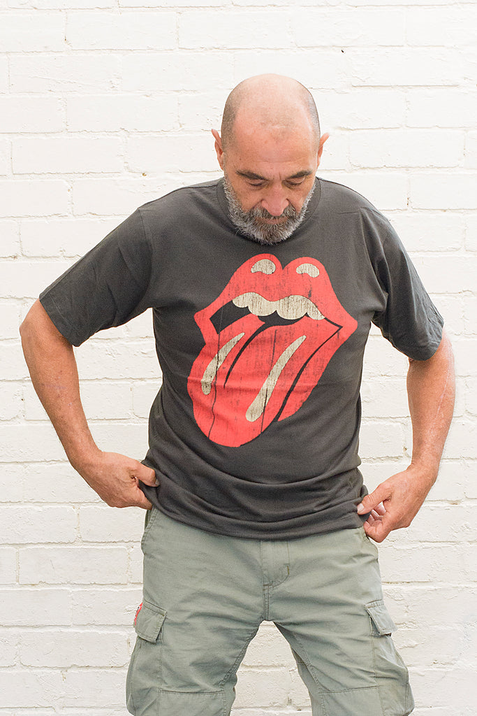 model wearing black cotton t-shirt with rolling stones tongue and lips logo printed on front