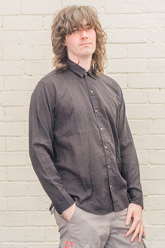 model wearing black cotton button up long sleeved collared shirt from the front