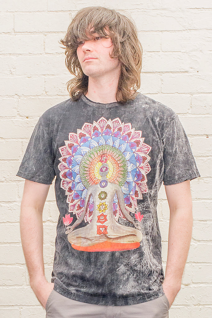 model wearing a black stonewash t-shirt printed with an image of a yoga practitioner in lotus position with the 7 chakras illustrated and with a mandala behind the character viewed from the front