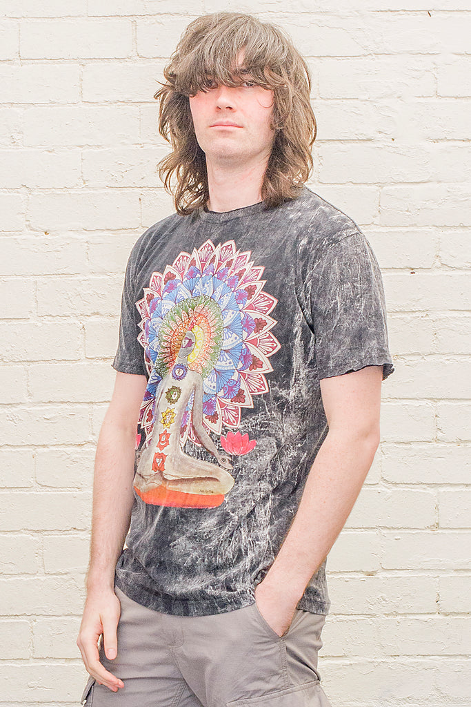 model wearing a black stonewash t-shirt printed with an image of a yoga practitioner in lotus position with the 7 chakras illustrated and with a mandala behind the character viewed from the front