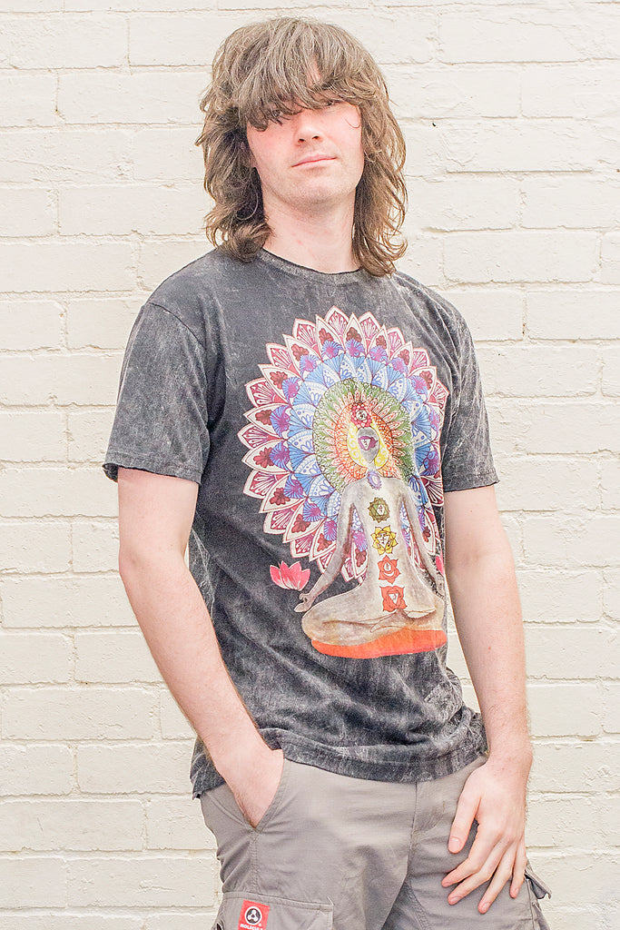 model wearing a black stonewash t-shirt printed with an image of a yoga practitioner in lotus position with the 7 chakras illustrated and with a mandala behind the character viewed from the front