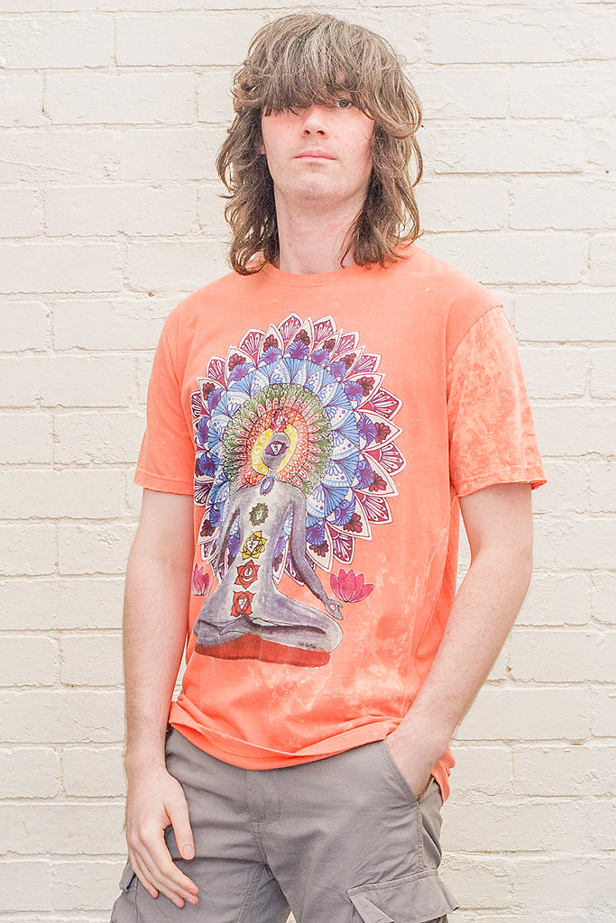 model wearing an orange stonewash t-shirt printed with an image of a yoga practitioner in lotus position with the 7 chakras illustrated and with a mandala behind the character viewed from the front