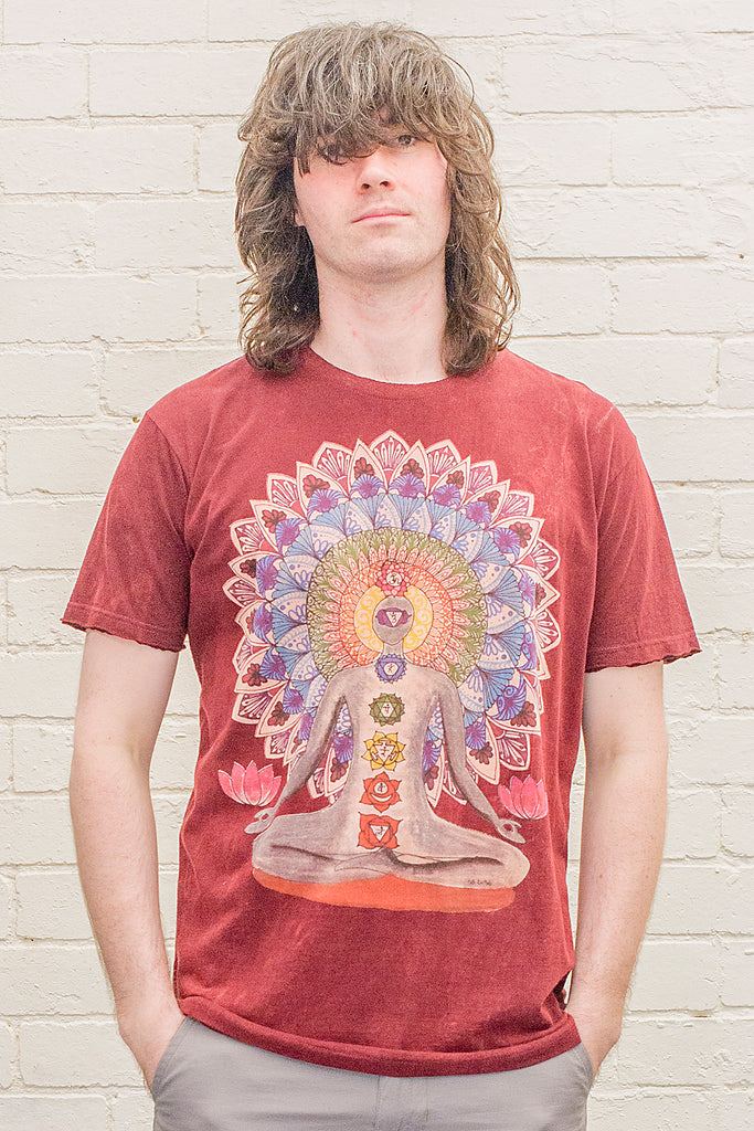 model wearing a dark red or maroon stonewash t-shirt printed with an image of a yoga practitioner in lotus position with the 7 chakras illustrated and with a mandala behind the character viewed from the front