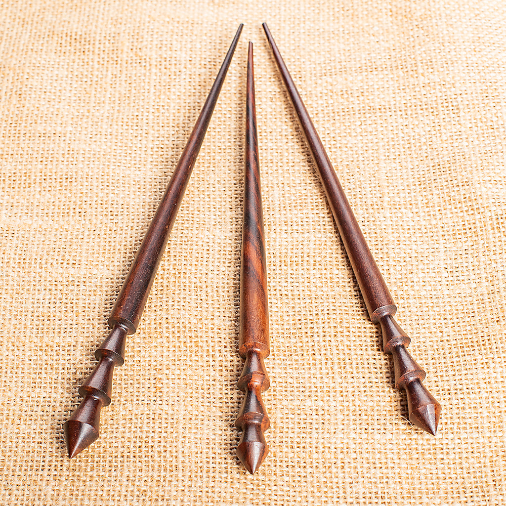 slender conical wooden hair stick with angular ornaments carved at end