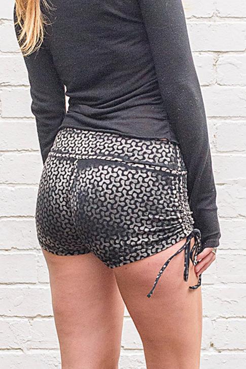 Model wearing black and white tessellated print shorts with ties at each side from back