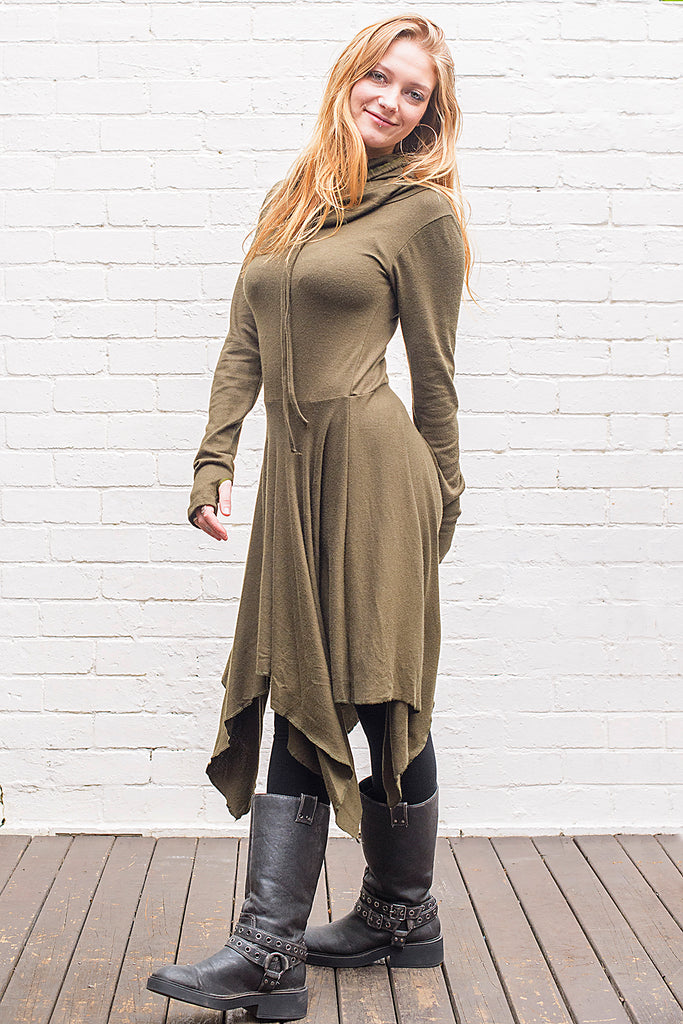 Model wearing a skadi midi length handkerchief hemline knit dress with hoodie and thumbholes in army green from side