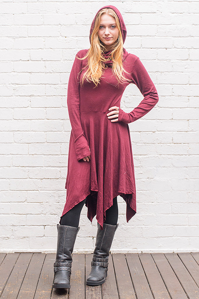 Model wearing a skadi midi length handkerchief hemline knit dress with hoodie and thumbholes in maroon