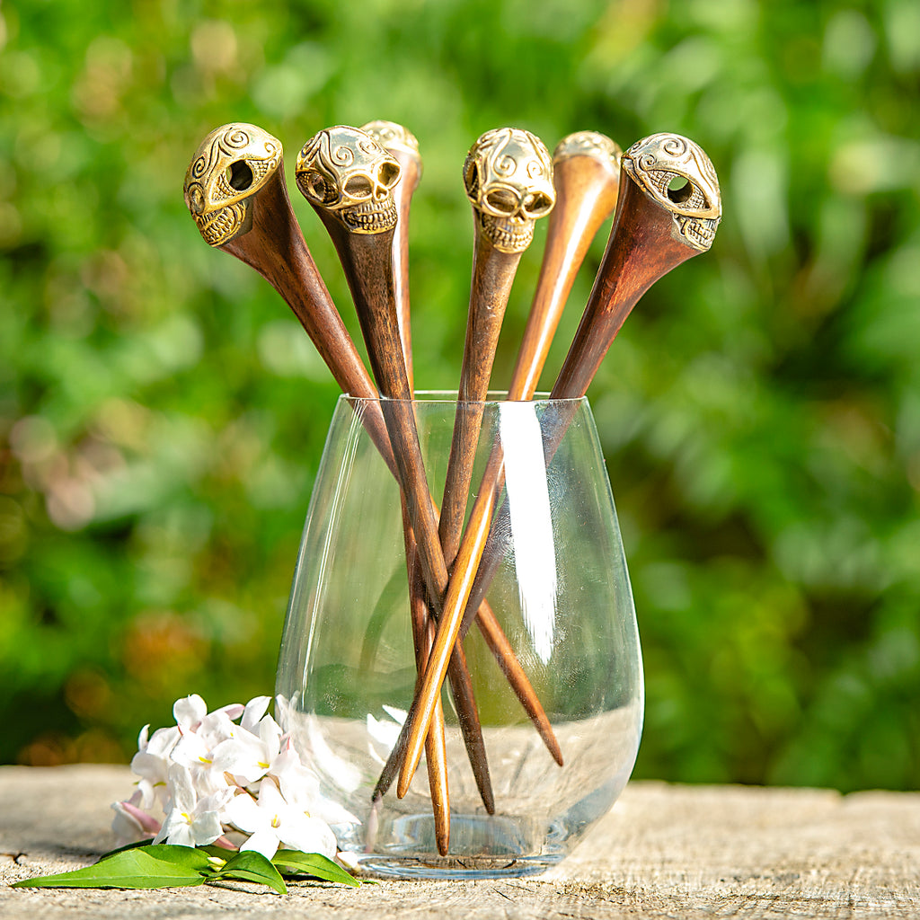 wooden hair stick with ornate carved brass skull at end