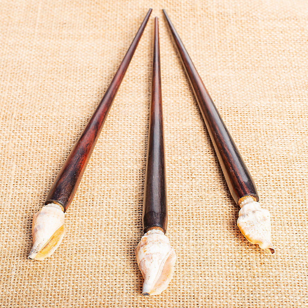 wooden hair stick with ornate cream and orange toned sea shell at end