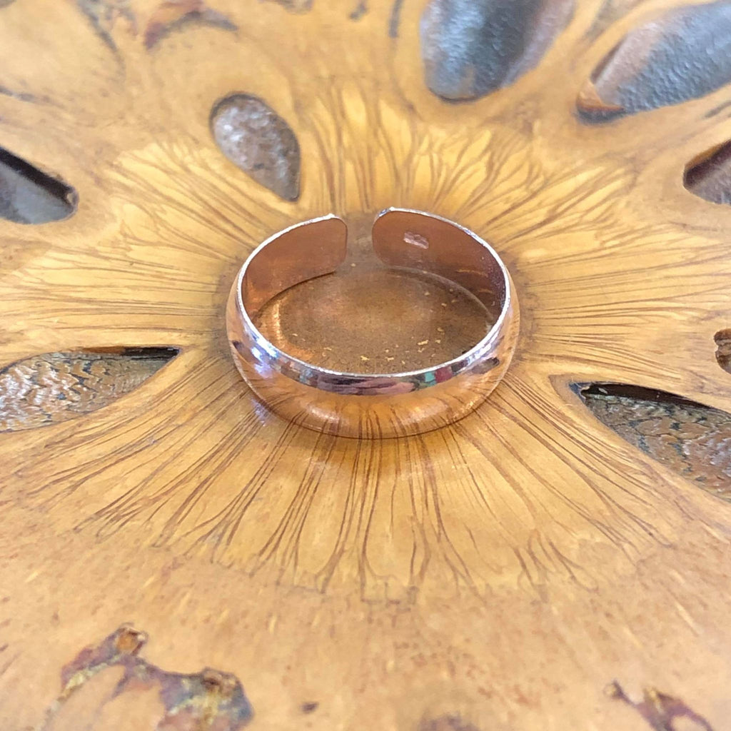 A rose gold plain band classic toe ring on a wooden background