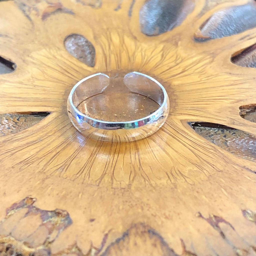 A silver plain band classic toe ring on a wooden background