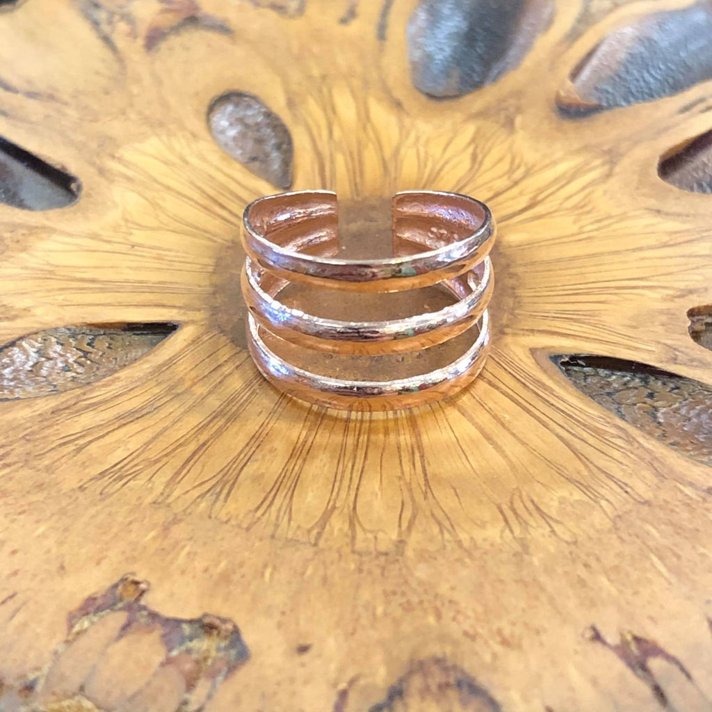 A rose gold triple band ring on a wooden background
