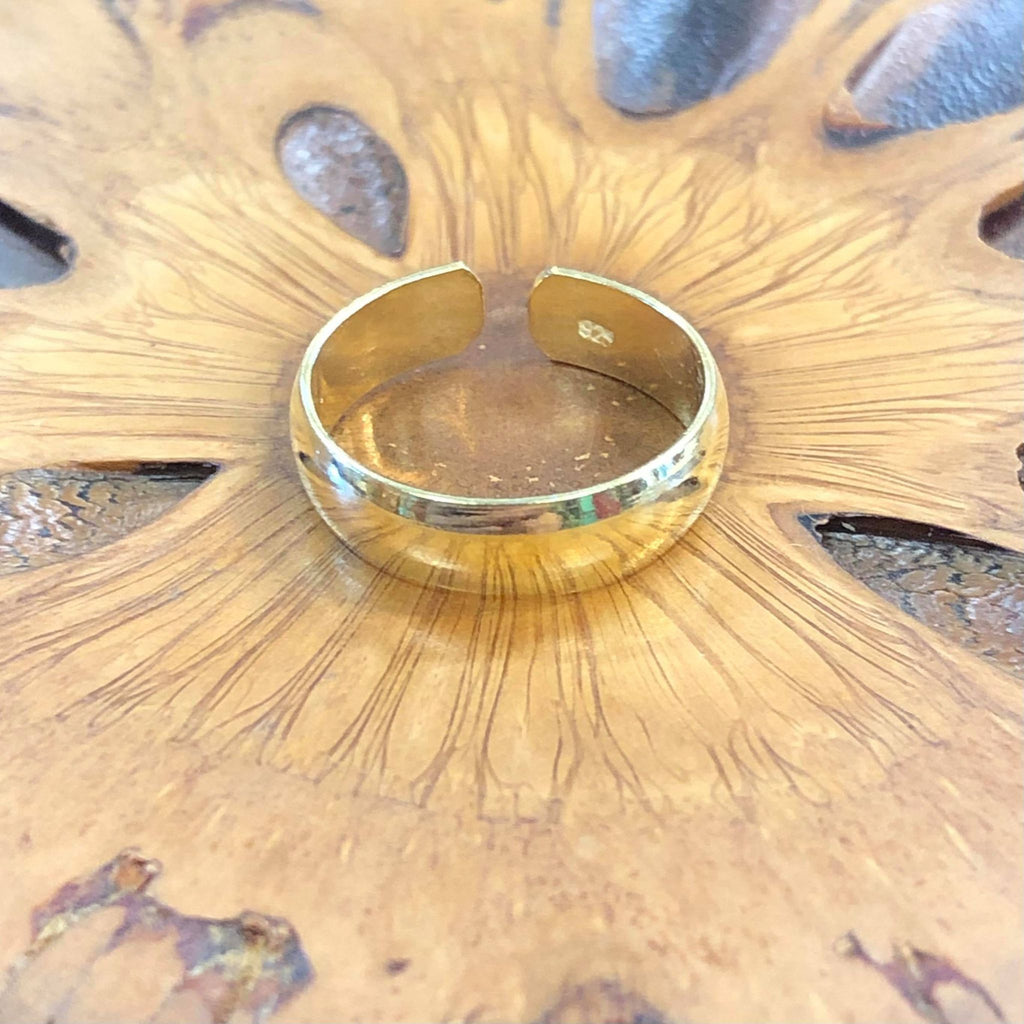A gold plain band classic toe ring on a wooden background