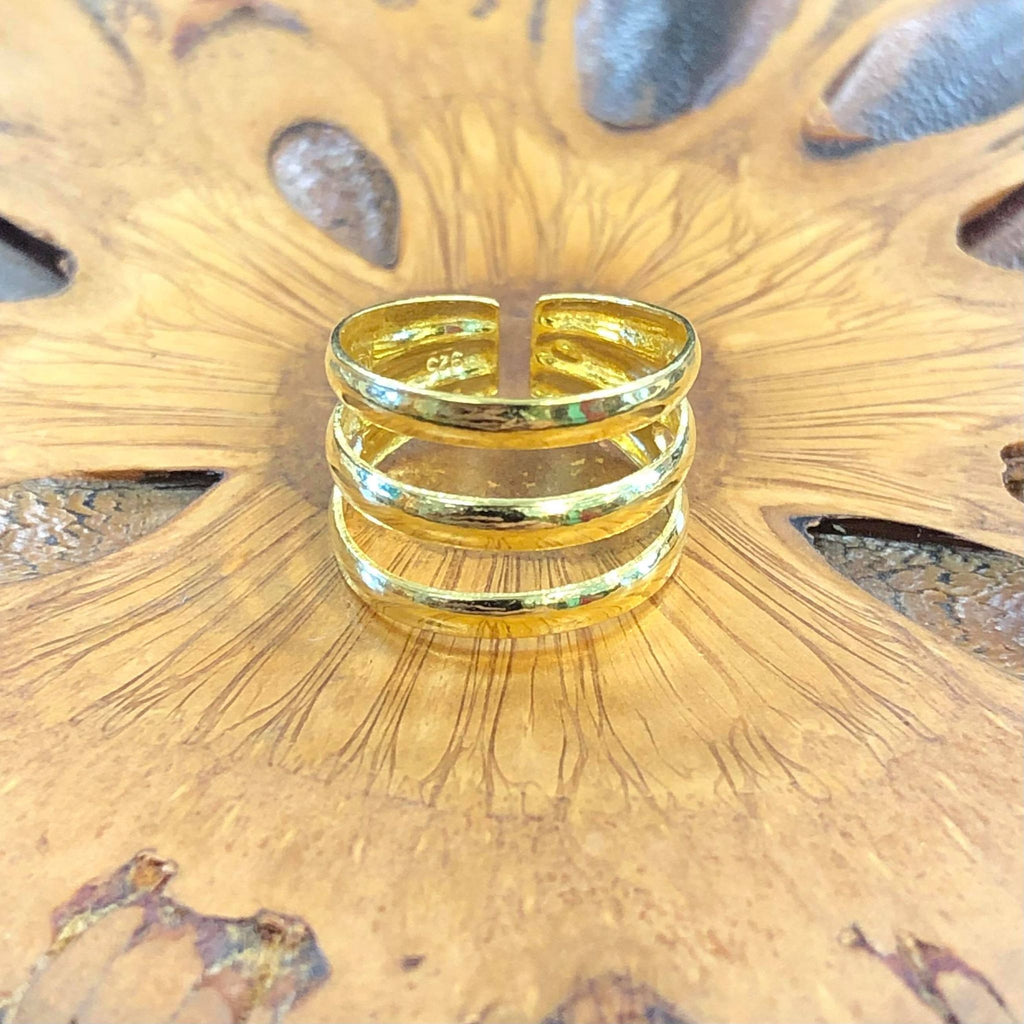 A gold triple band ring on a wooden background