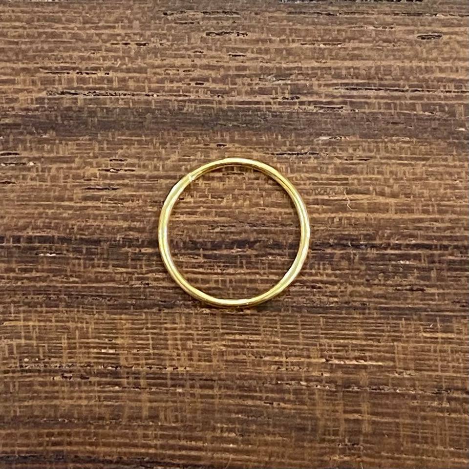A small gold sleeper earring on a wooden background