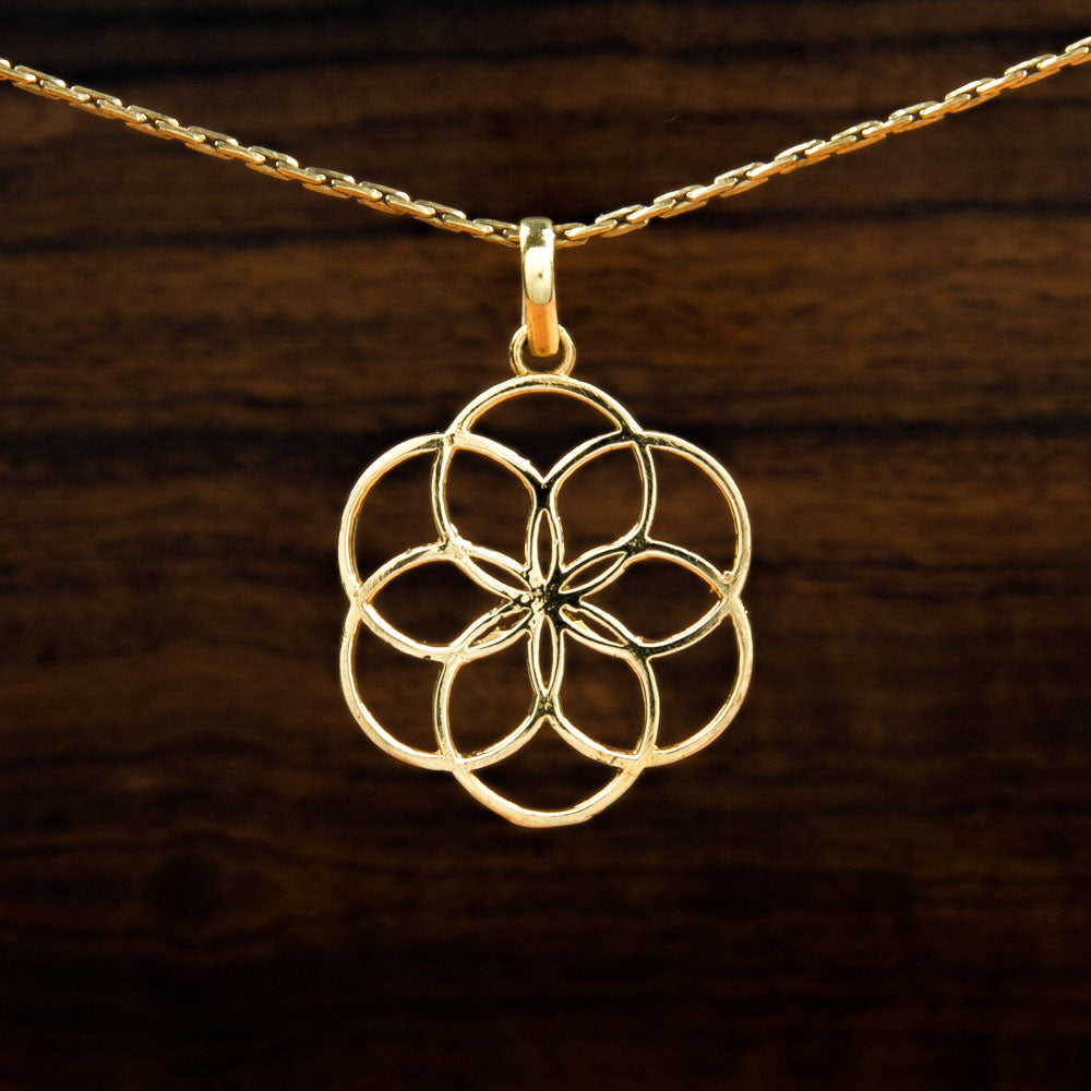 A brass pendant featuring a flower of life design on a wooden background
