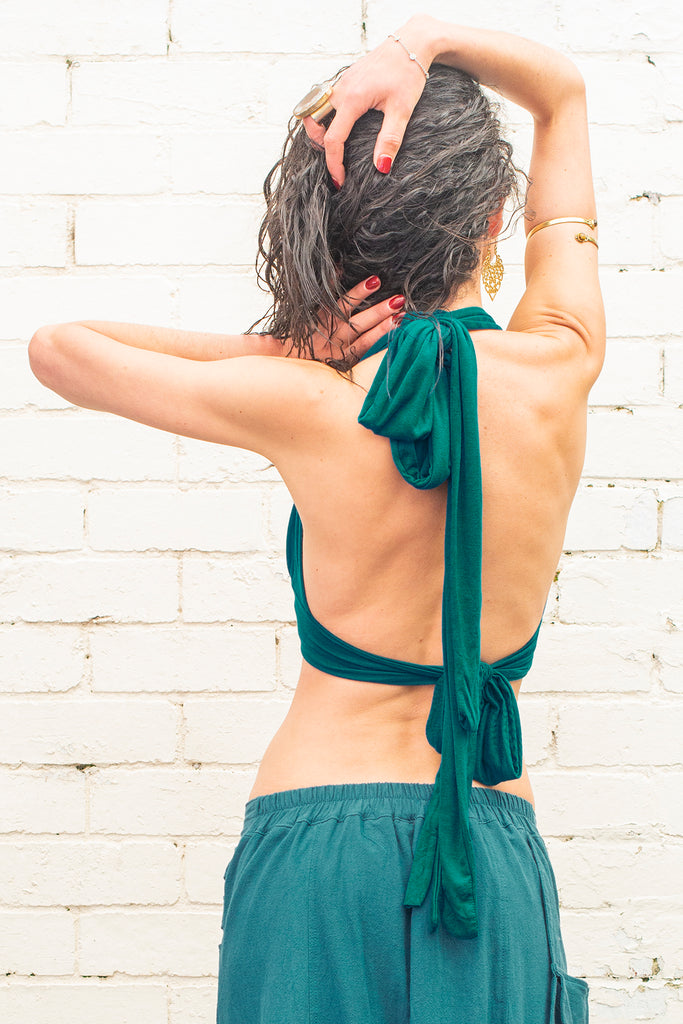 back of a model wearing a crop top with adjustable stripes in teal colour on a white background