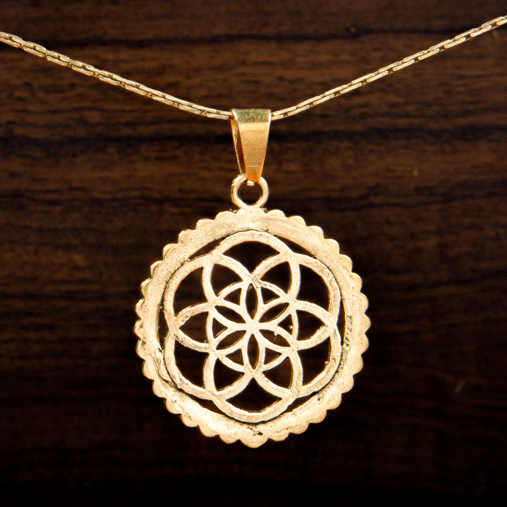 A Brass pendant featuring a flower of life design inside a circle