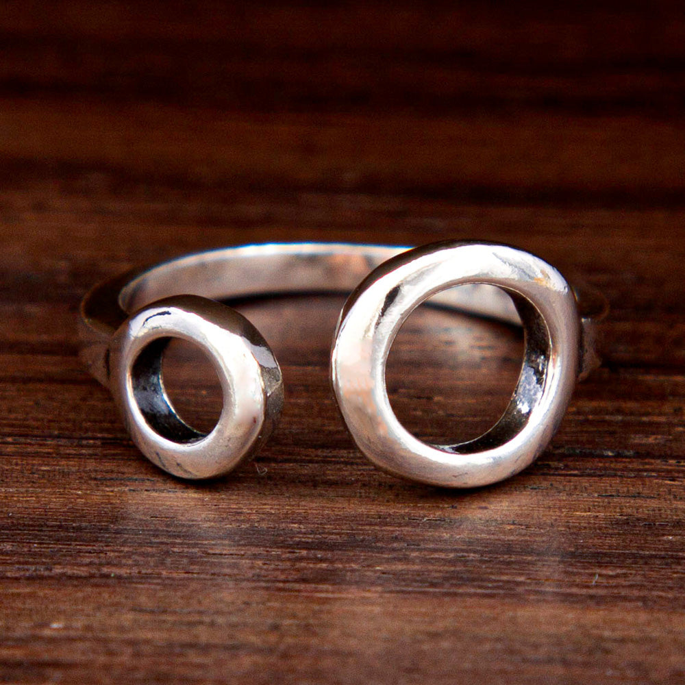 A silver ring featuring two circles of different size on a wooden background