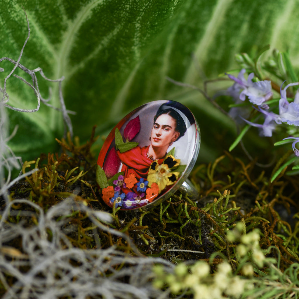 san marco silver and resin adjustable ring with photograph of frida kahlo wearing a scarlet or orange scarf with colourful dried flowers and set in resin