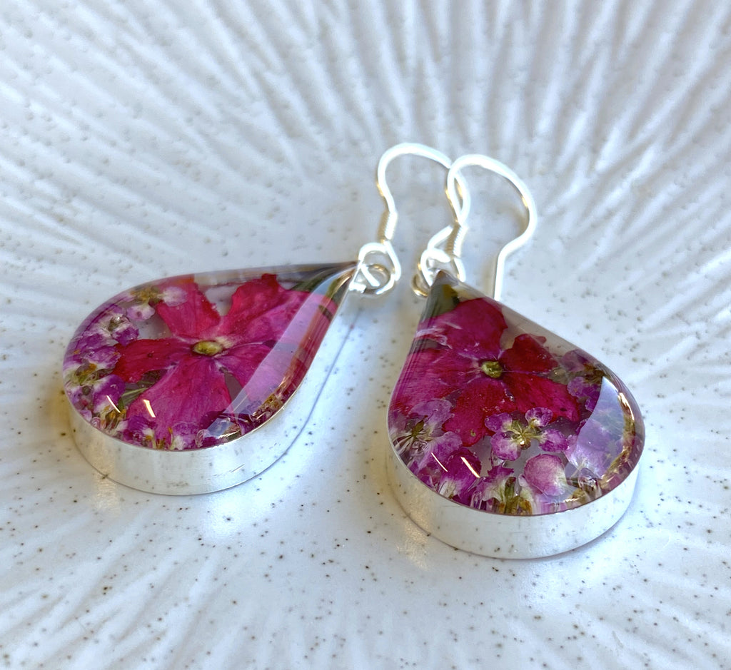 san marco medium length teardrop shaped silver and resin earrings with dried purplish pink flowers encased in the resin