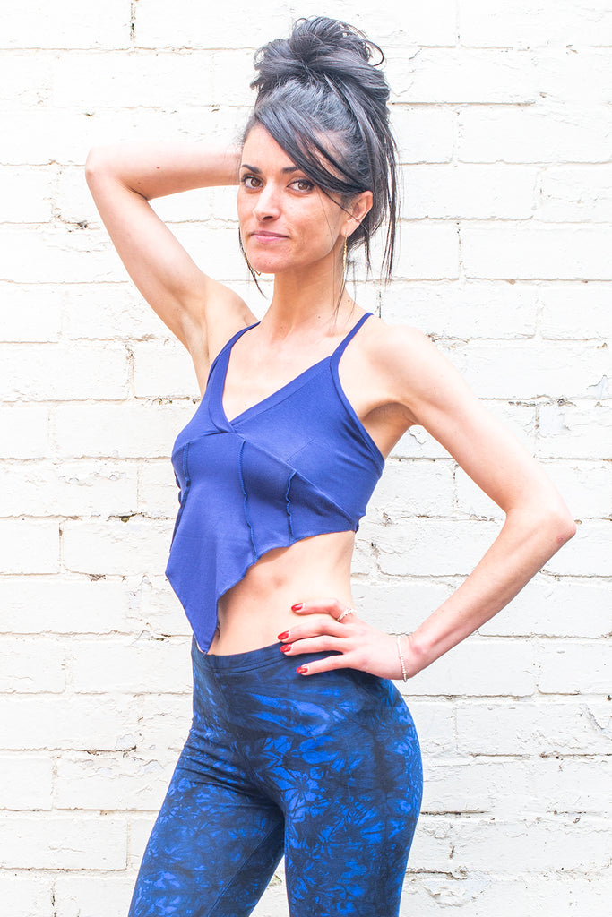 A woman wearing a blue crop top and blue leggings on a white background