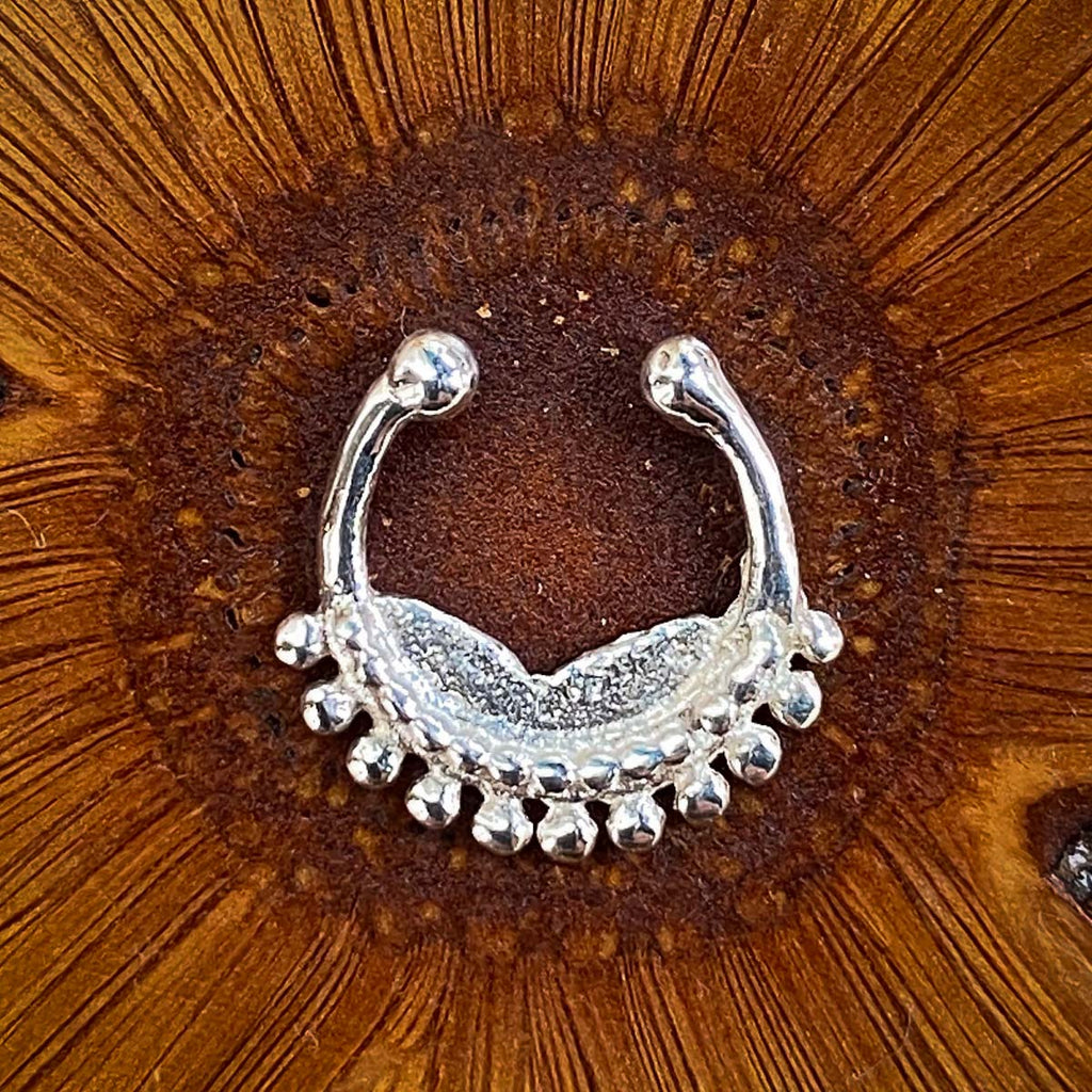 A fake septum jewel made of sterling silver on a wooden background