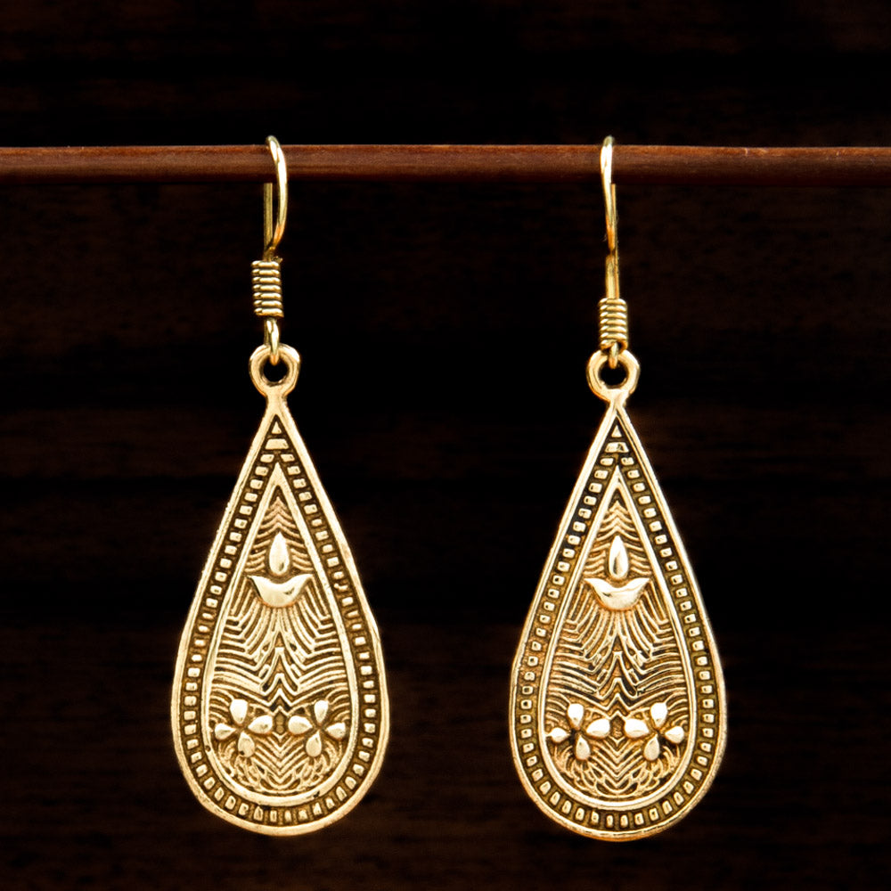 Teardrop shaped brass earrings engraved with earthy ancient graphic