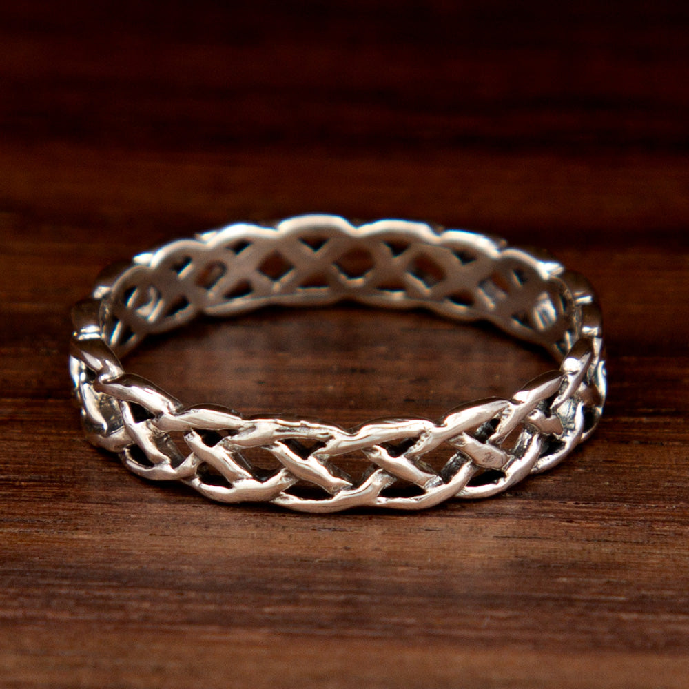 A sterling silver ring featuring a plait design on a wooden background