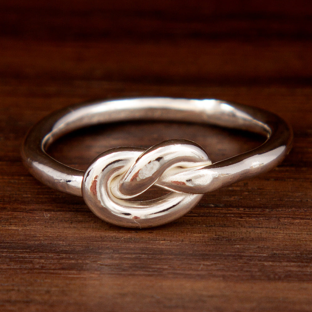 A ring silver featuring a knot design on a wooden background